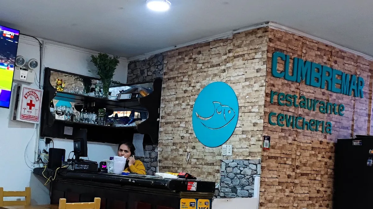 El salón de Cumbremar: mesas de madera y su letrero de restaurante cevichería en la pared de ladrillo